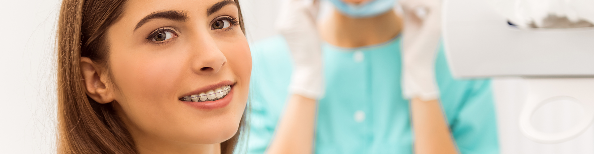 dentist standing behind smiling girl with braces